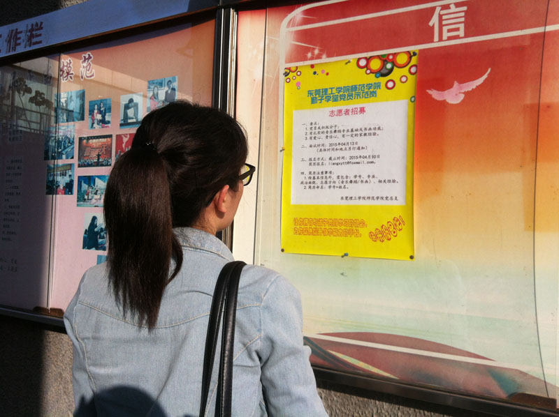 学生正在看招募志愿者的海报-800